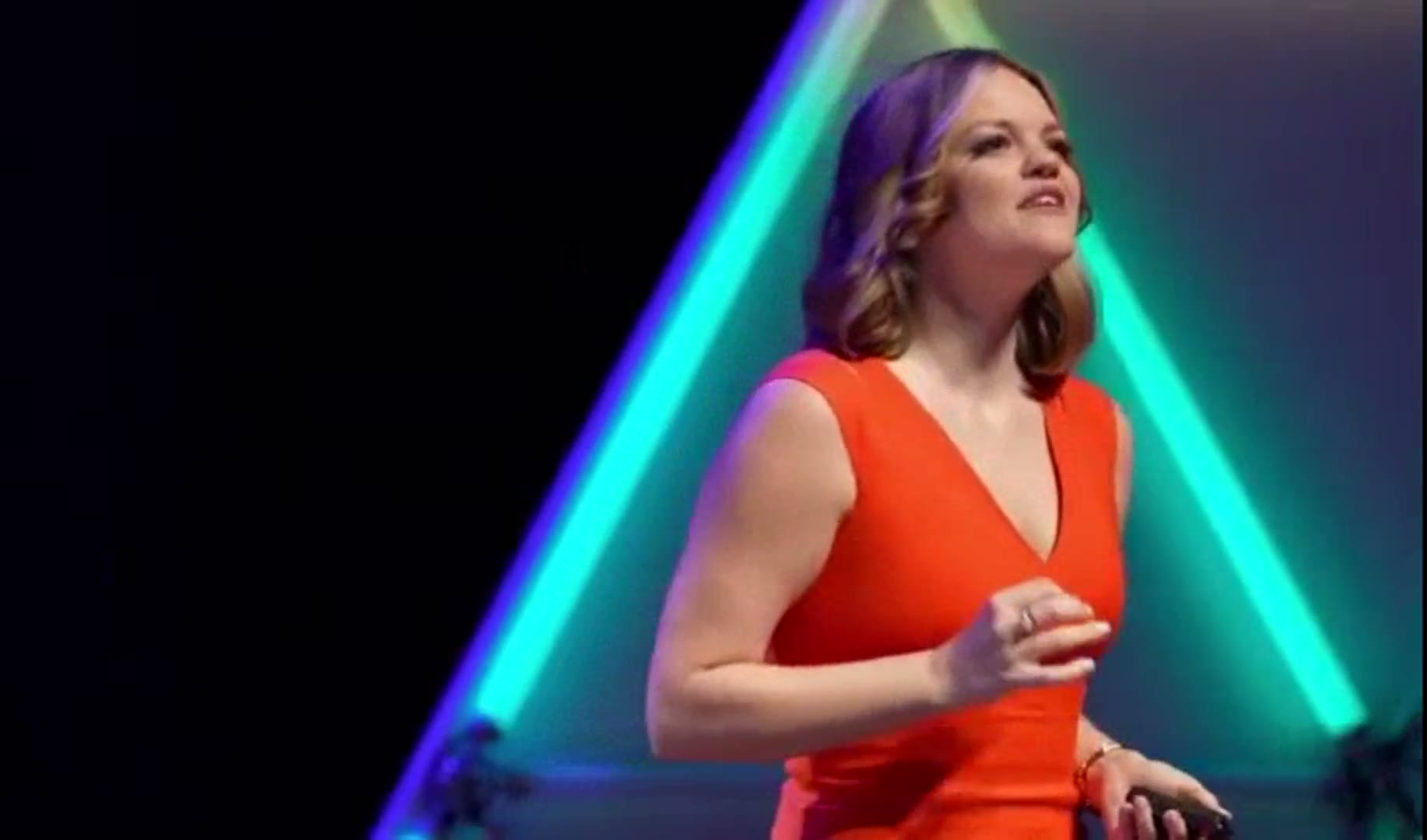 Kirsty Hulse speaking on stage in a red dress